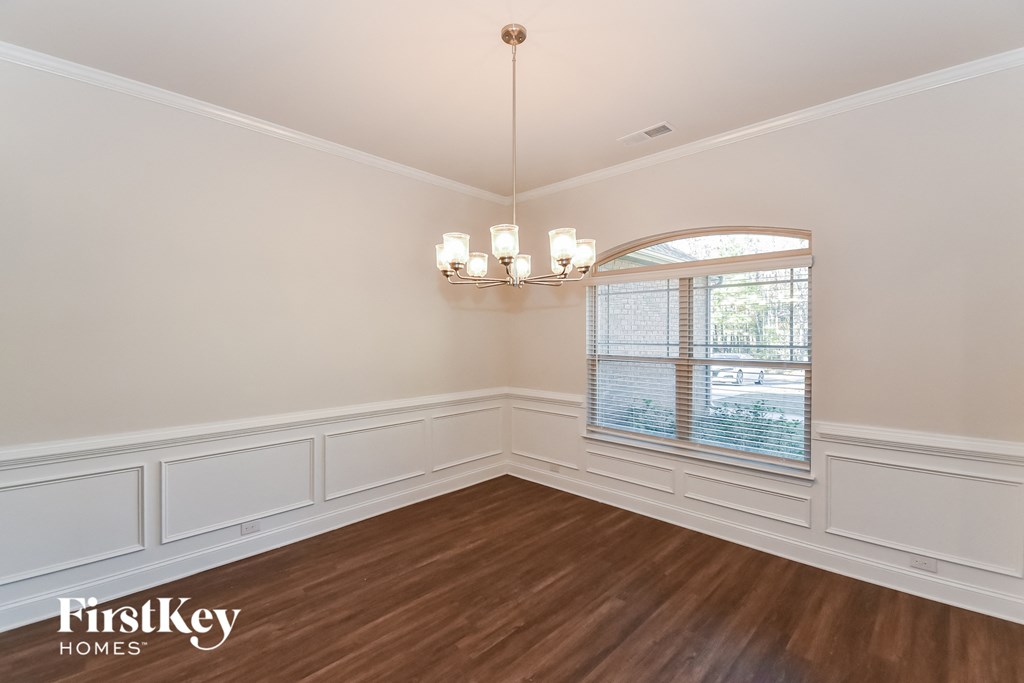 A well-lit room with wooden floors and a chandelier.