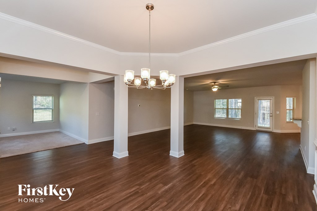 A large, empty room with wooden floors and a chandelier.