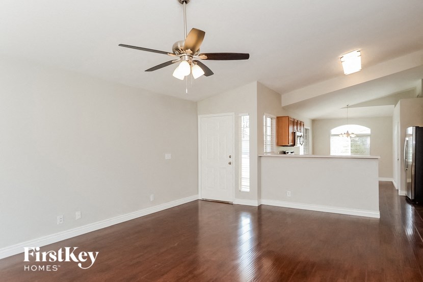 an empty living room with a ceiling fan and a kitchen