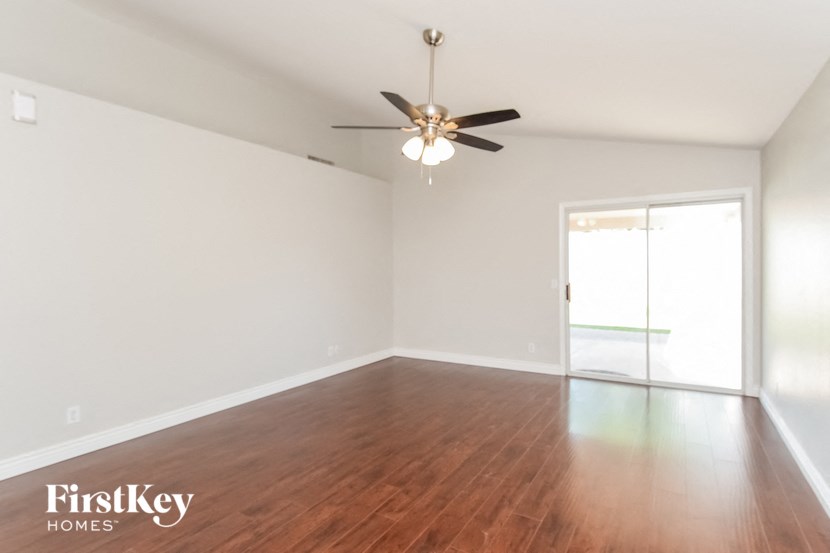 an empty living room with wood floors and a ceiling fan