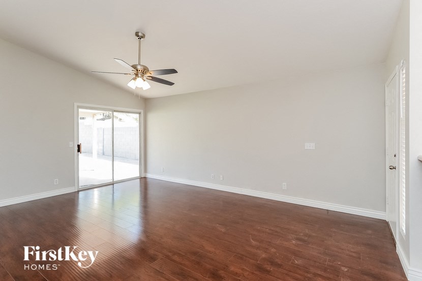 an empty living room with wood flooring and a ceiling fan