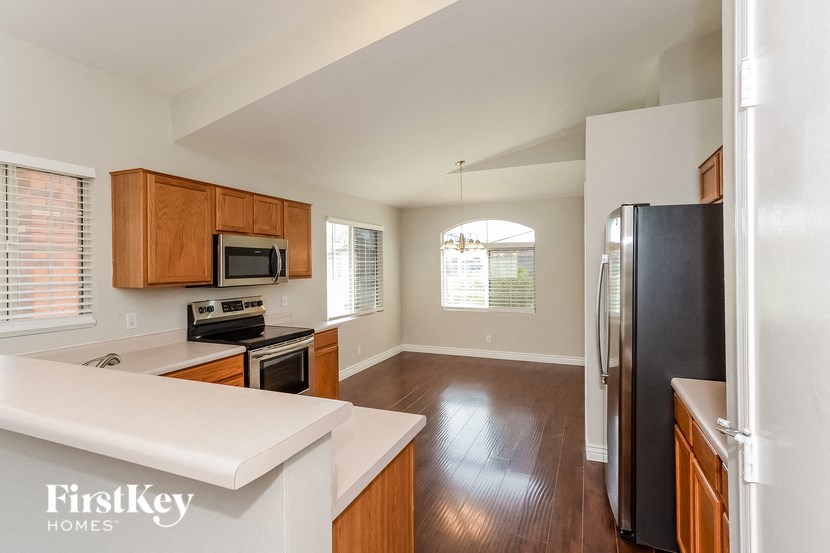 an empty kitchen with wood floors and a black refrigerator