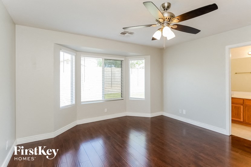 an empty living room with a ceiling fan and windows