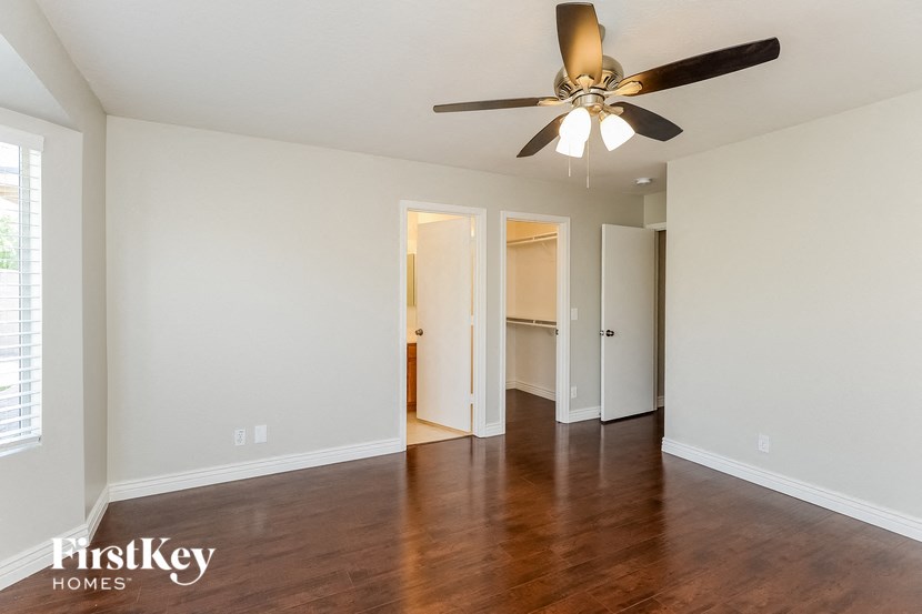 an empty living room with wood floors and a ceiling fan