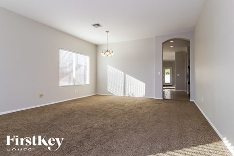 A spacious room with a carpeted floor and a chandelier hanging from the ceiling.