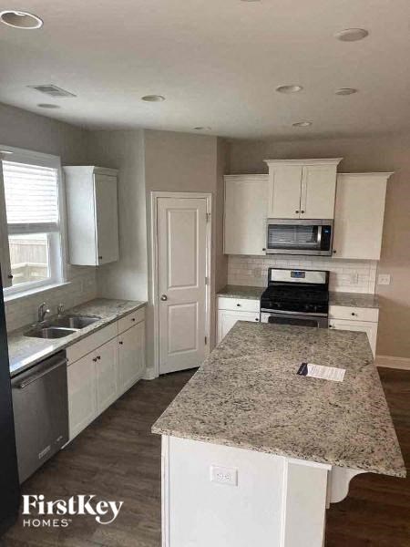 a kitchen with white cabinets and a marble counter top