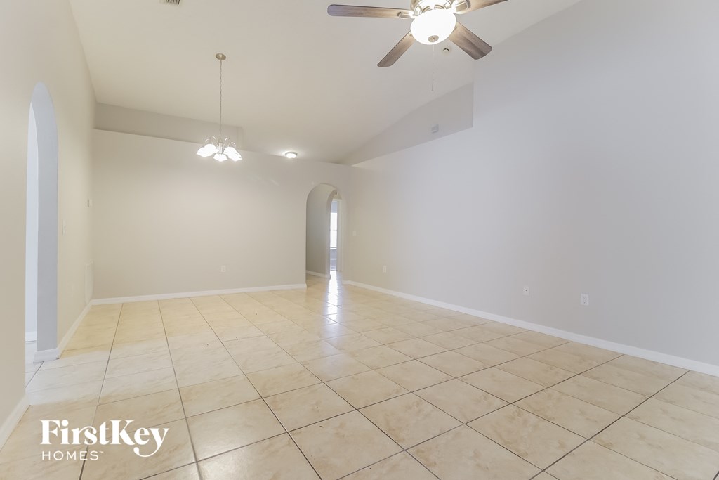 a empty living room with a ceiling fan and tiled floors