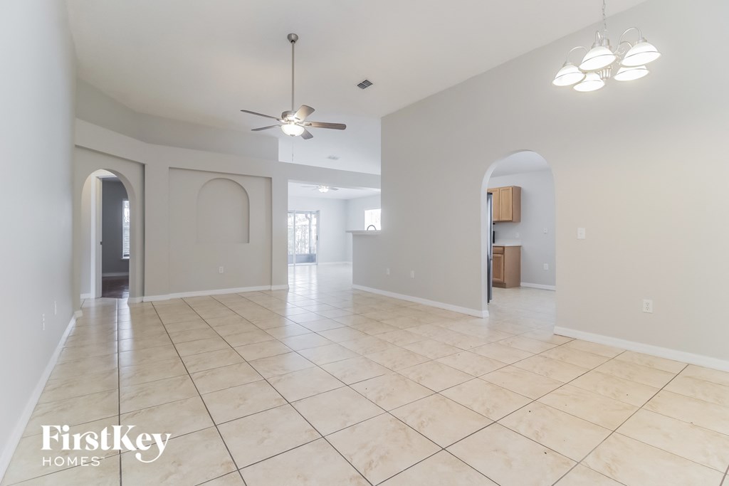 a large empty living room with tile floors and a ceiling fan