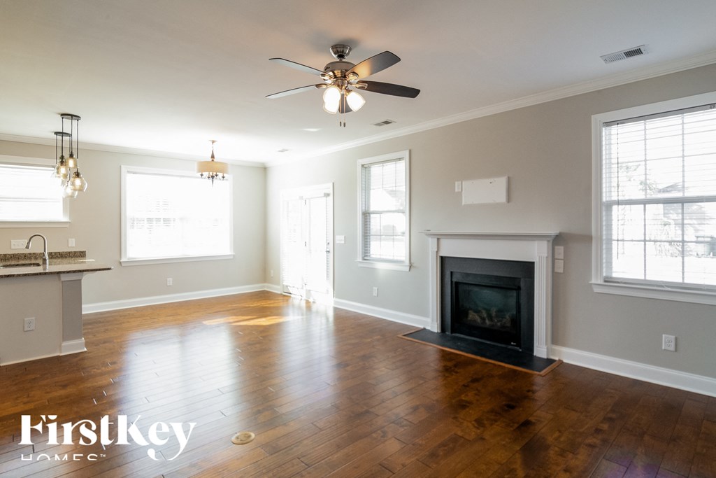A spacious living room with a fireplace and a ceiling fan.