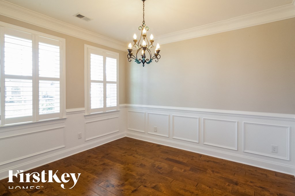 A room with a chandelier and wooden floors.