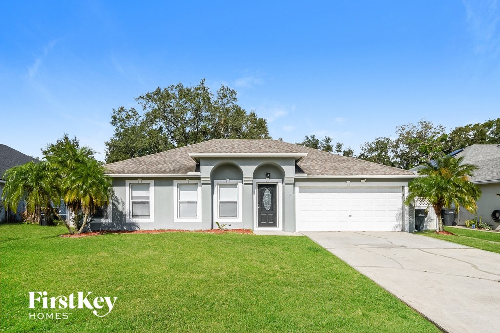 a white house with a lawn and palm trees