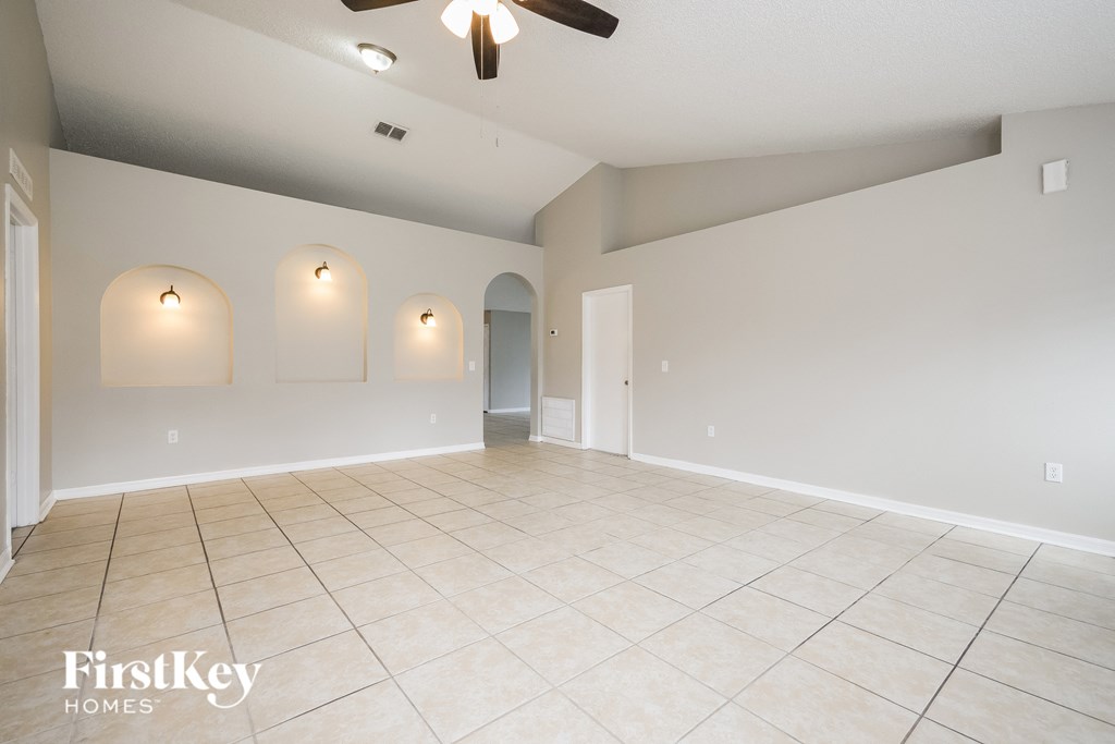 a empty living room with a ceiling fan and a tile floor