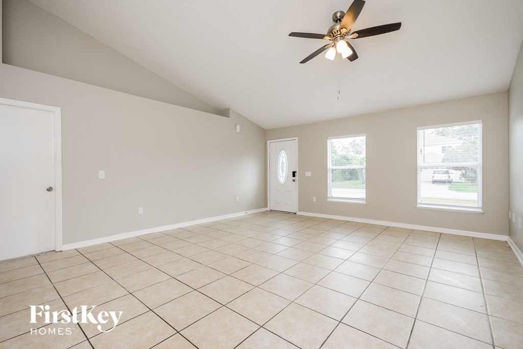 a clean and empty living room with a ceiling fan
