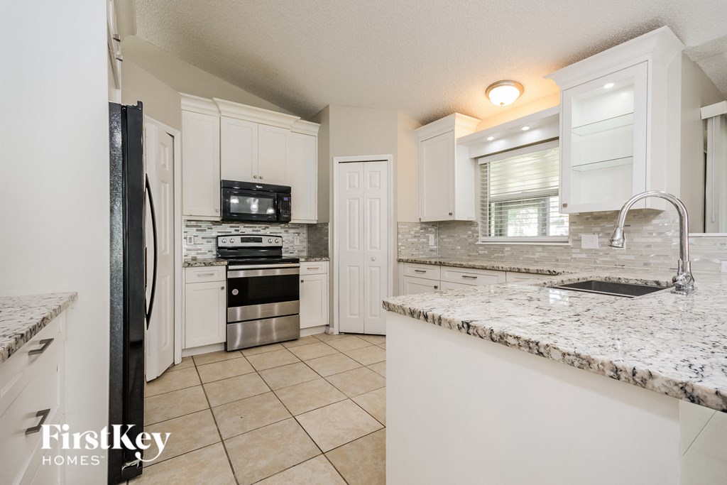 a kitchen with white cabinets and granite counter tops