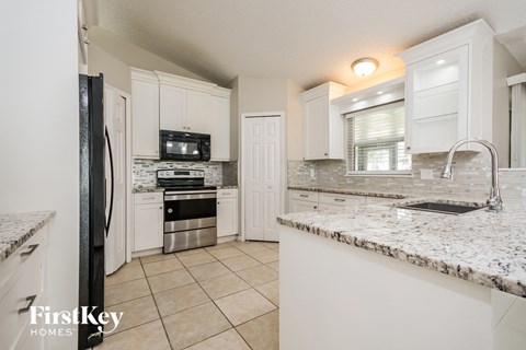a kitchen with white cabinets and granite counter tops