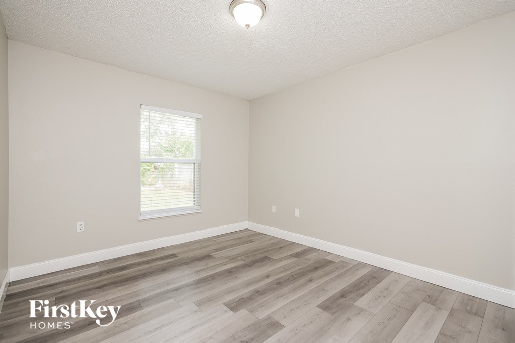 the spacious living room with hardwood flooring and a window