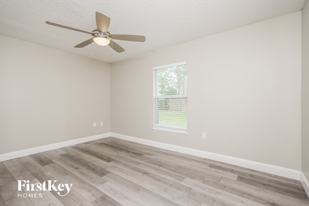a bedroom with wood flooring and a ceiling fan