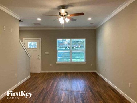 an empty living room with a ceiling fan and a window