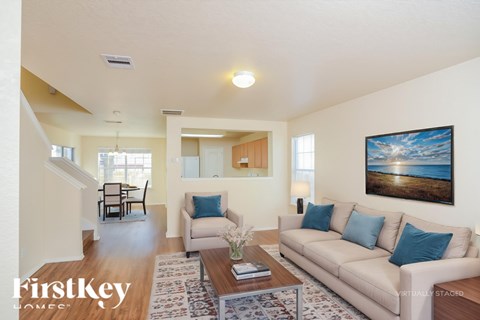 A living room with a couch, chairs, and a painting on the wall.