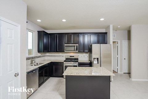 a kitchen with black cabinets and white marble counter tops and stainless steel appliances