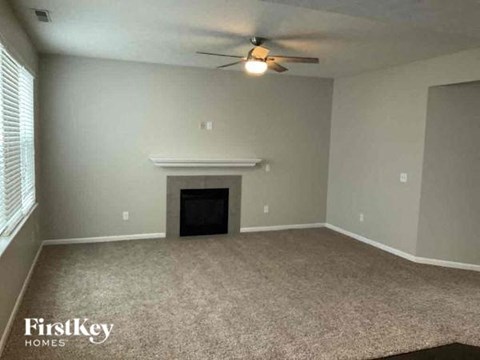 an empty living room with a ceiling fan and a fireplace