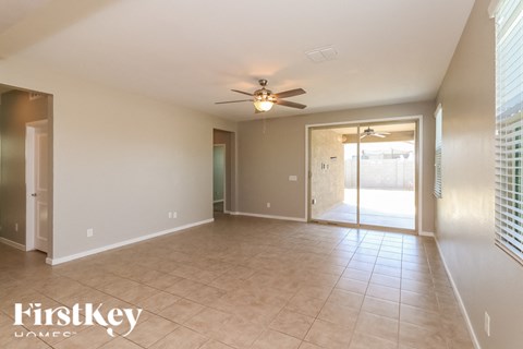 A spacious room with a ceiling fan and sliding glass doors leading to a balcony.