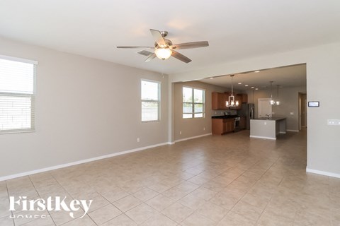 A spacious living room with a ceiling fan and tiled flooring.