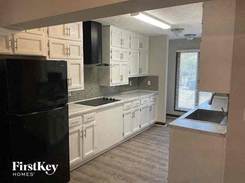 A kitchen with white cabinets and a black refrigerator.