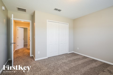 a bedroom with white doors and carpeting and a door to a hallway