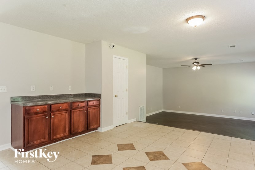 a empty living room with a kitchen and a ceiling fan