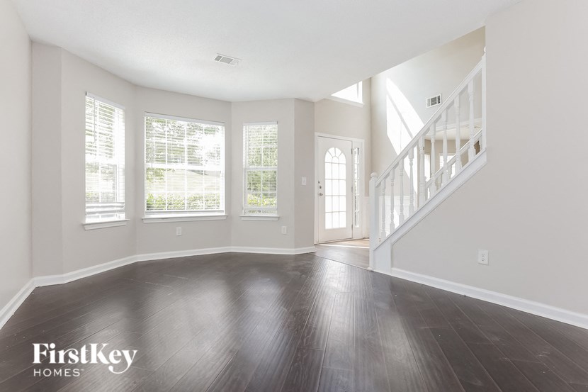 an empty living room with wood floors and a staircase