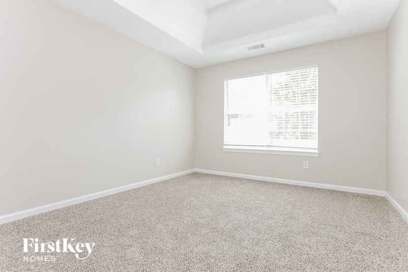 a bedroom with a window and carpeted floor