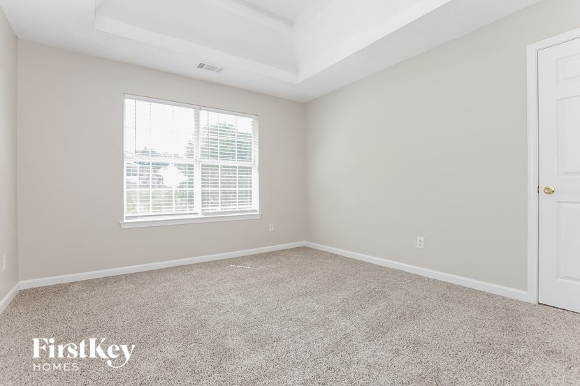 a bedroom with a window and carpeted floor