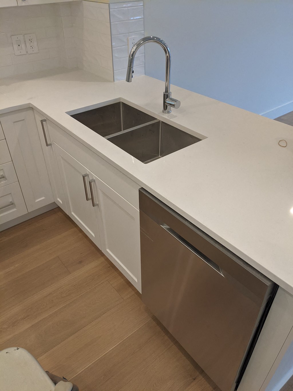a white kitchen with a stainless steel sink and counter top