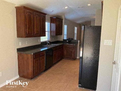 A kitchen with wooden cabinets and a black refrigerator.