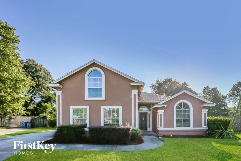 a pink house with white trim and a green lawn