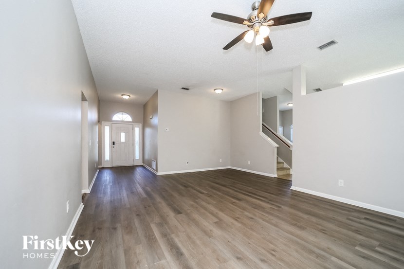 an empty living room with wood flooring and a ceiling fan