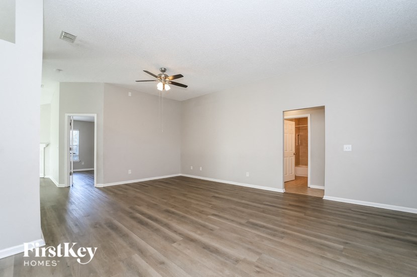 an empty living room with wood flooring and a ceiling fan