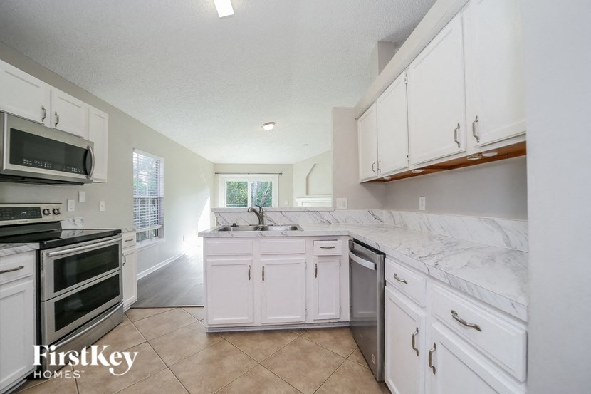 a large kitchen with white cabinets and stainless steel appliances
