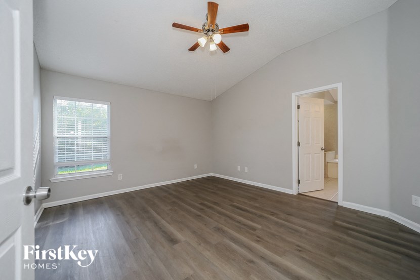 an empty living room with wood floors and a ceiling fan