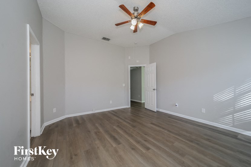 an empty living room with wood flooring and a ceiling fan
