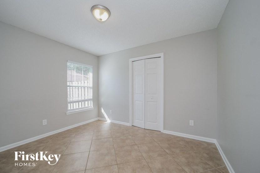 an empty living room with a white door and tile flooring
