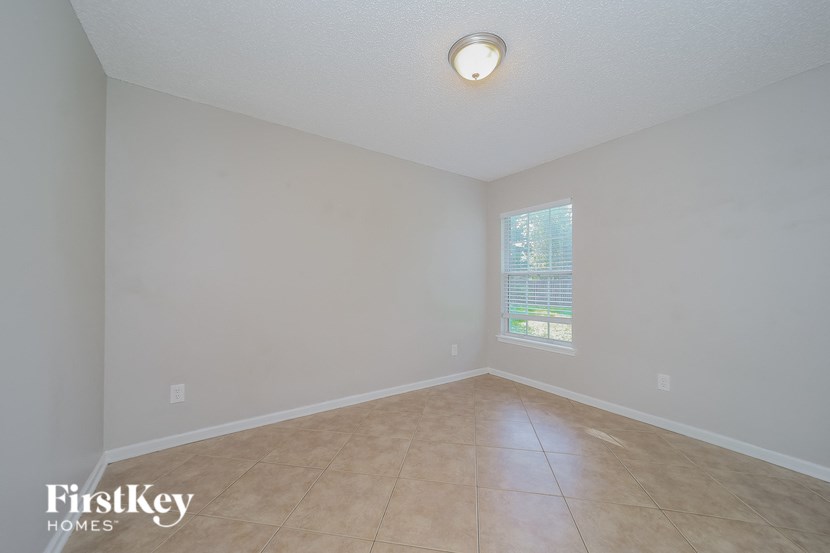 an empty living room with a window and tiled floors