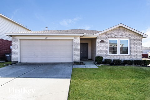 a white brick house with a white garage door and a lawn