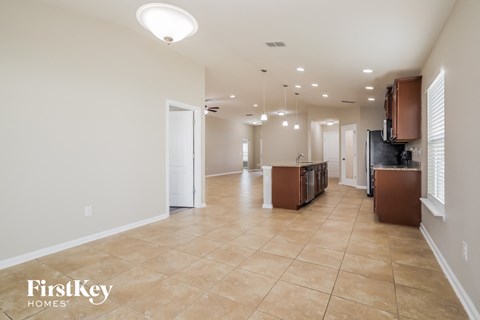 a large kitchen and living room with a large tile floor and white walls