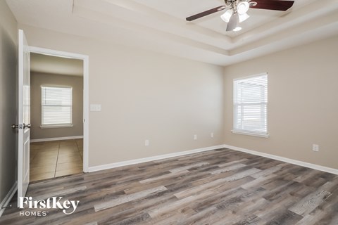 the spacious living room with wood flooring and a ceiling fan