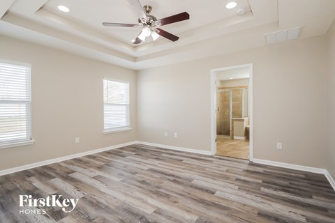 the spacious living room with hardwood flooring and a ceiling fan
