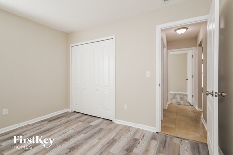 a bedroom with a white door and a hallway with wood floors