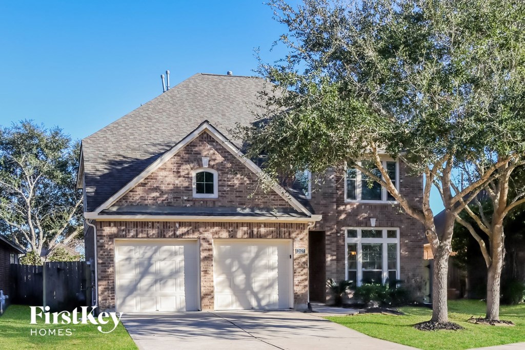 a large brick house with a garage and trees