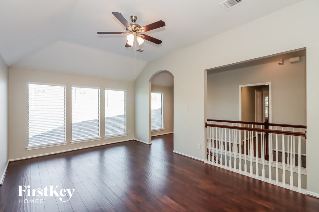 an empty living room with wood floors and a ceiling fan
